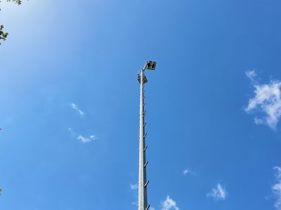 Stalen lichtmast met LED-armaturen tegen een blauwe lucht