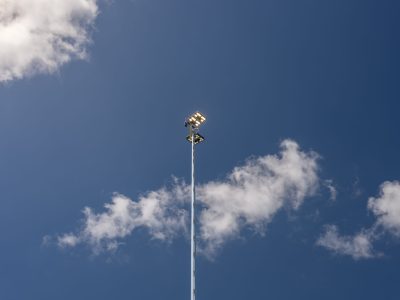 Hoge stalen lichtmast van Mastendepot met schijnwerpers tegen een blauwe lucht