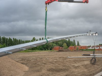 Lichtmast van Mastendepot wordt met een kraan geplaatst op een terrein