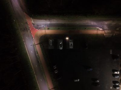 Luchtfoto bij nacht van een verlicht parkeerterrein en toegangsweg